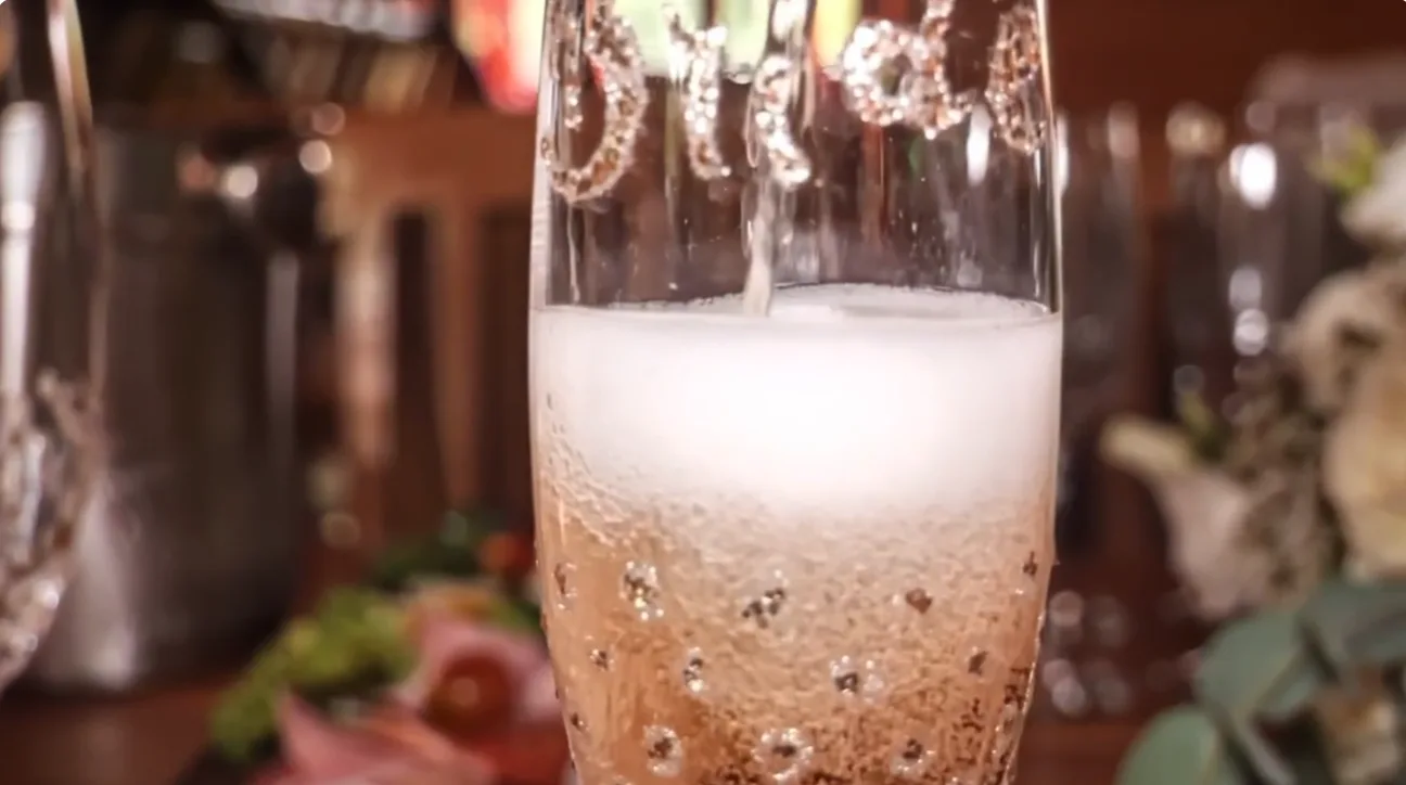 Close view of sparkling champagne being poured into a crystal glass in an opulent room.